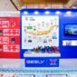 A display booth featuring Valvoline GEELY collaboration, showcasing co-developed lubricants and a timeline of their partnership, with product bottles arranged on a central table.